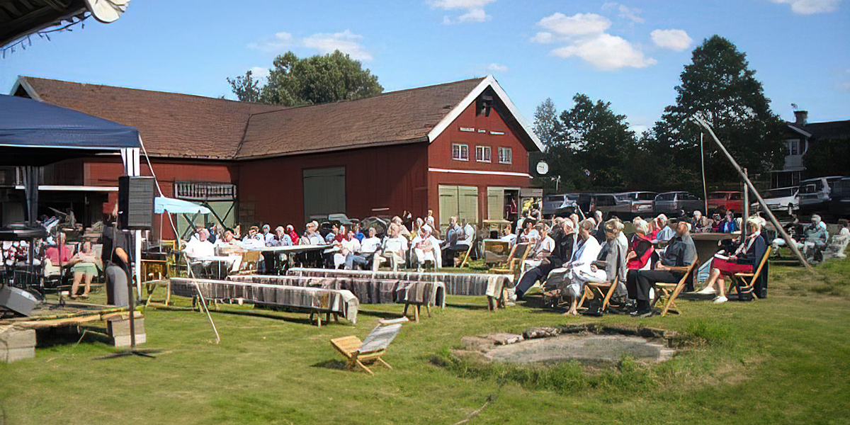 Bild på en stor grupp människor som sitter på en gårdsplan och lyssnar på musik